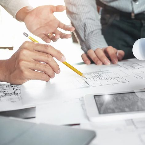 Close-up of professionals reviewing architectural plans at a table